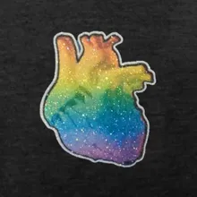 Close up of an anatomical heart overlayed with a rainbow gradient glitter printed on a black heathered t-shirt.