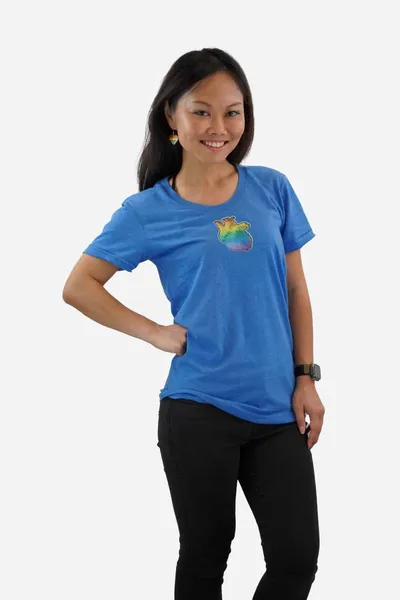 An anatomical heart overlayed with a rainbow gradient glitter printed on a blue t-shirt, worn by a young asian woman.