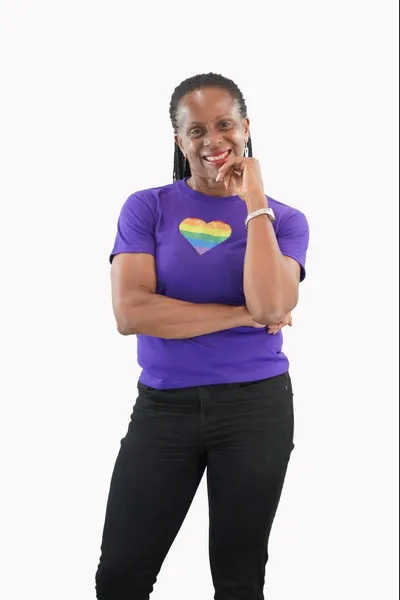 Classic pride flag in the shape of a heart glitter printed on a purple tank top, worn by a black woman.